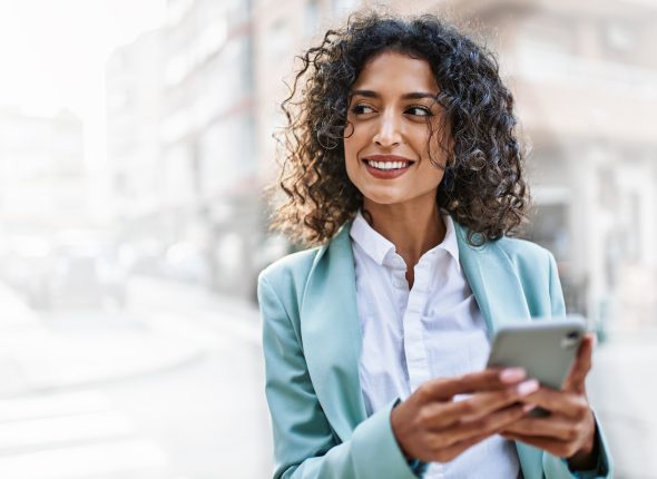 Young hispanic business woman wearing professional look smiling confident at the city using smartphone
